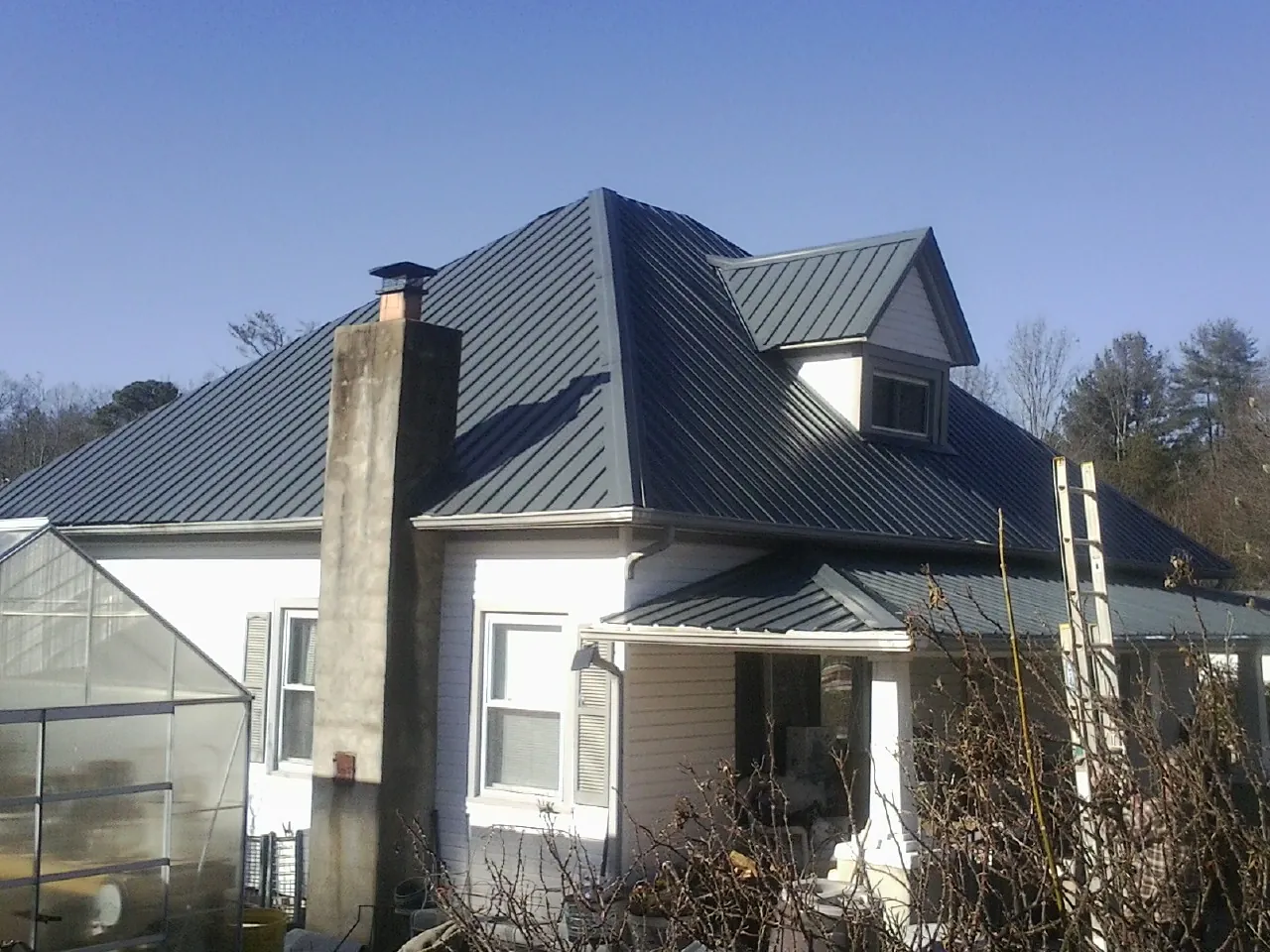 Dark blue standing seam metal roof on a white farmhouse with dormer — Slate & Tile Roof Repair by Roofing Brothers in West Chester